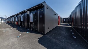 Una hilera de edificios de estilo industrial con puertas numeradas, probablemente parte de un complejo comercial o industrial.