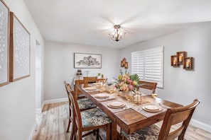 Comedor con una mesa de madera dispuesta para seis personas, rodeada de sillas con tapicería floral.