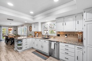 A modern kitchen with white cabinetry, granite countertops, and a central island.