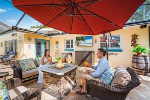 A patio area with outdoor seating, a fire pit, and a large umbrella.