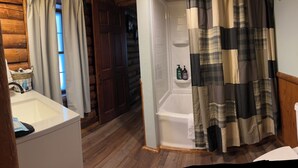Un baño con suelo de madera, un lavamanos blanco, una bañera y un inodoro.