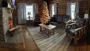 Interior acogedor de una cabaña de madera con chimenea, una mesa de centro de madera, un sofá y un árbol de Navidad.