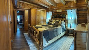 Un dormitorio estilo cabaña con estructura de cama de madera, una mesita de noche y un aparador.