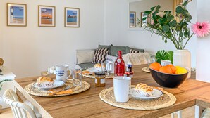 Een eetruimte met een houten tafel gedekt voor het ontbijt, inclusief borden, bekers en een schaal met fruit.