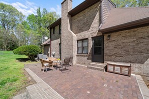 Une maison à deux étages, construite en briques, avec un patio comprenant une table et des chaises.