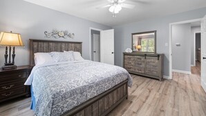 Une chambre à coucher avec un lit, une commode et un ventilateur de plafond.