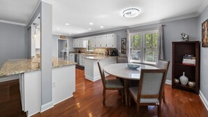 Une cuisine moderne dotée de plans de travail en granit, de meubles blancs et d’un îlot central.