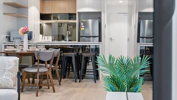 A modern kitchen with white cabinets, stainless steel appliances, and a dining area with wooden chairs and a table.