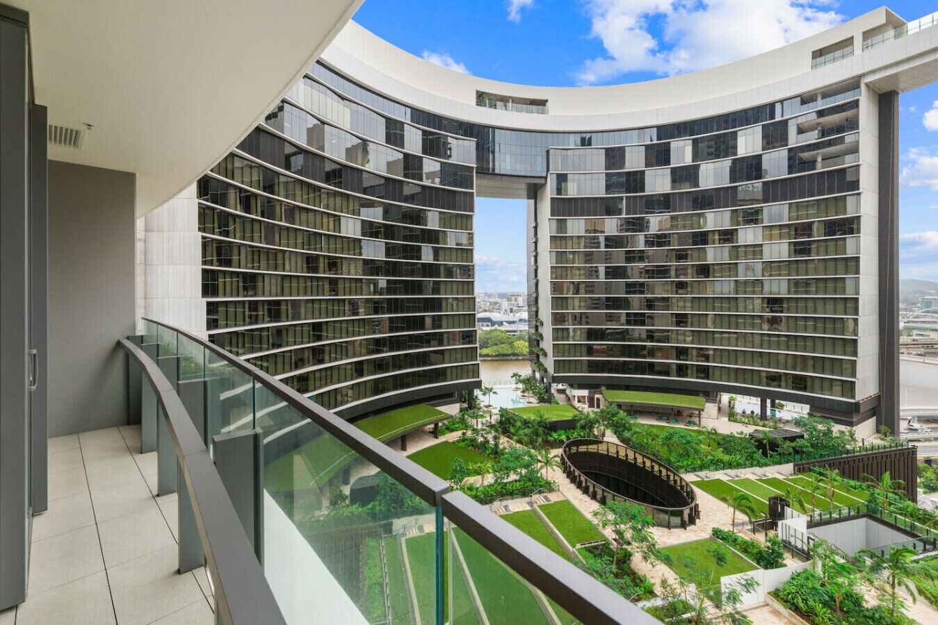A modern building with curved balconies and a central courtyard with greenery.