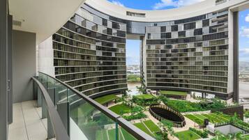 A modern building with curved balconies and a central courtyard with greenery.