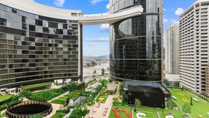 Un moderno complejo hotelero con fachada de vidrio curva, jardín en la azotea y zona de piscina circular.