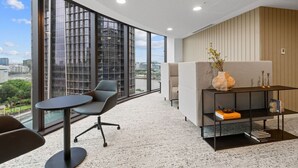 Un espacio de oficina moderno con ventanas amplias, una mesa redonda y un sofá.