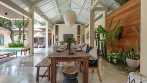 Un vaste espace de vie comprenant une table à manger en bois, des sièges confortables et une vue sur une piscine et un espace extérieur.