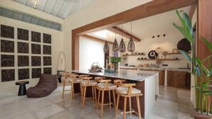 Une cuisine moderne dotée d’un grand îlot central, de tabourets de bar en bois et de divers éléments décoratifs.