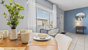 Un comedor moderno con una mesa de madera, sillas blancas y un jarrón con plantas verdes.