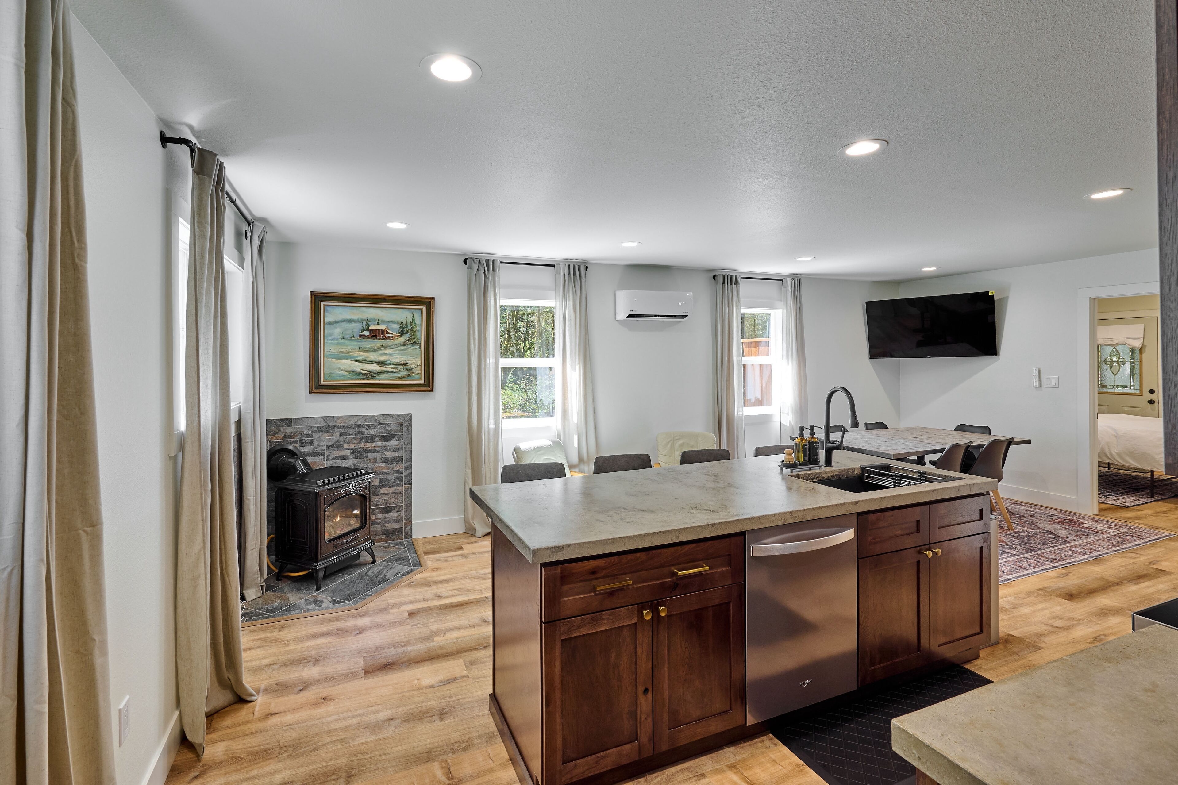 A modern kitchen with a central island, built-in cabinets, and a stone fireplace.