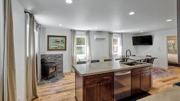 A modern kitchen with a central island, built-in cabinets, and a stone fireplace.