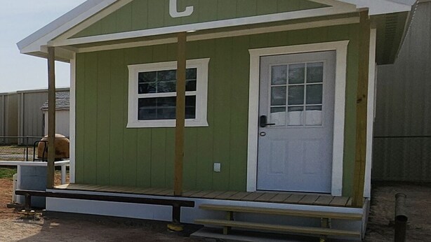 A small, single-story building with a green exterior and a white door. - Tinyhouse with AC and laundry area. Near Ector County Coliseum (Odessa)