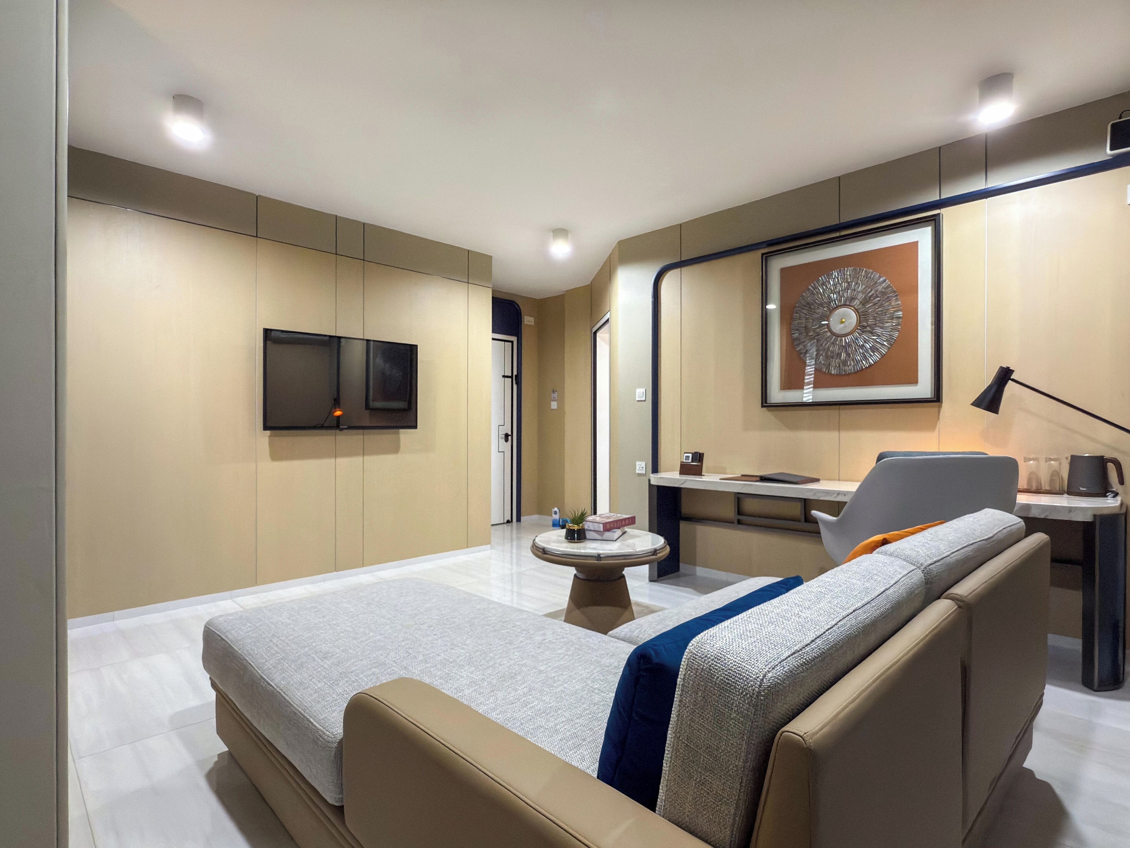 Una habitación de hotel moderna con una cama, un escritorio, una silla, un televisor y una obra de arte enmarcada en la pared.