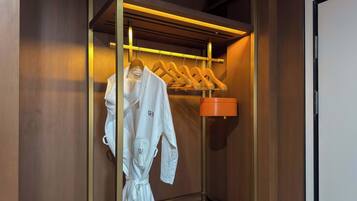 Ein begehbarer Kleiderschrank mit Holzvertäfelung, ein Bademantel an einem hölzernen Kleiderbügel und eine kleine, orangefarbene Aufbewahrungsbox.