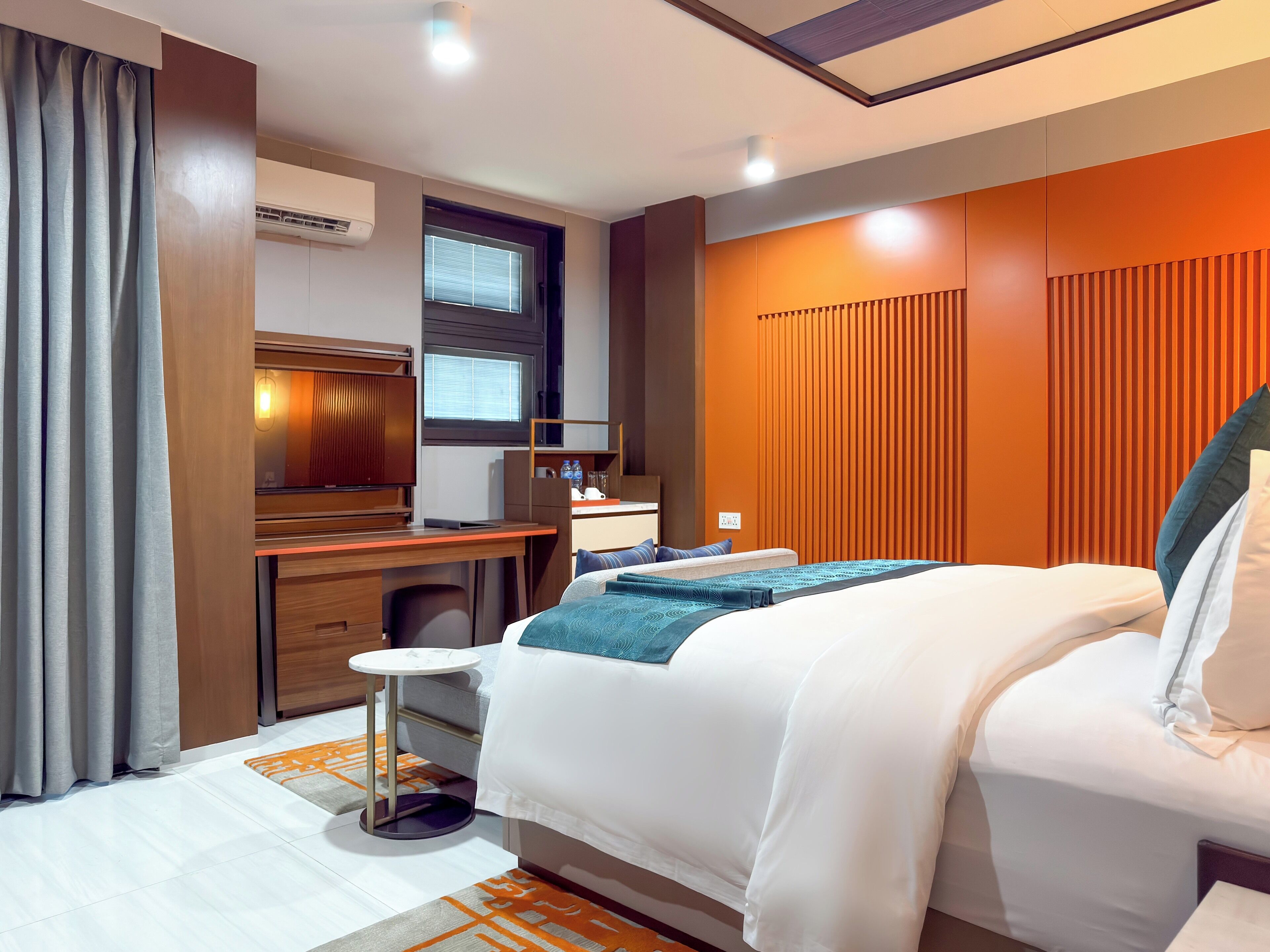 Une chambre d’hôtel moderne avec un grand lit, un bureau et une petite table ronde.
