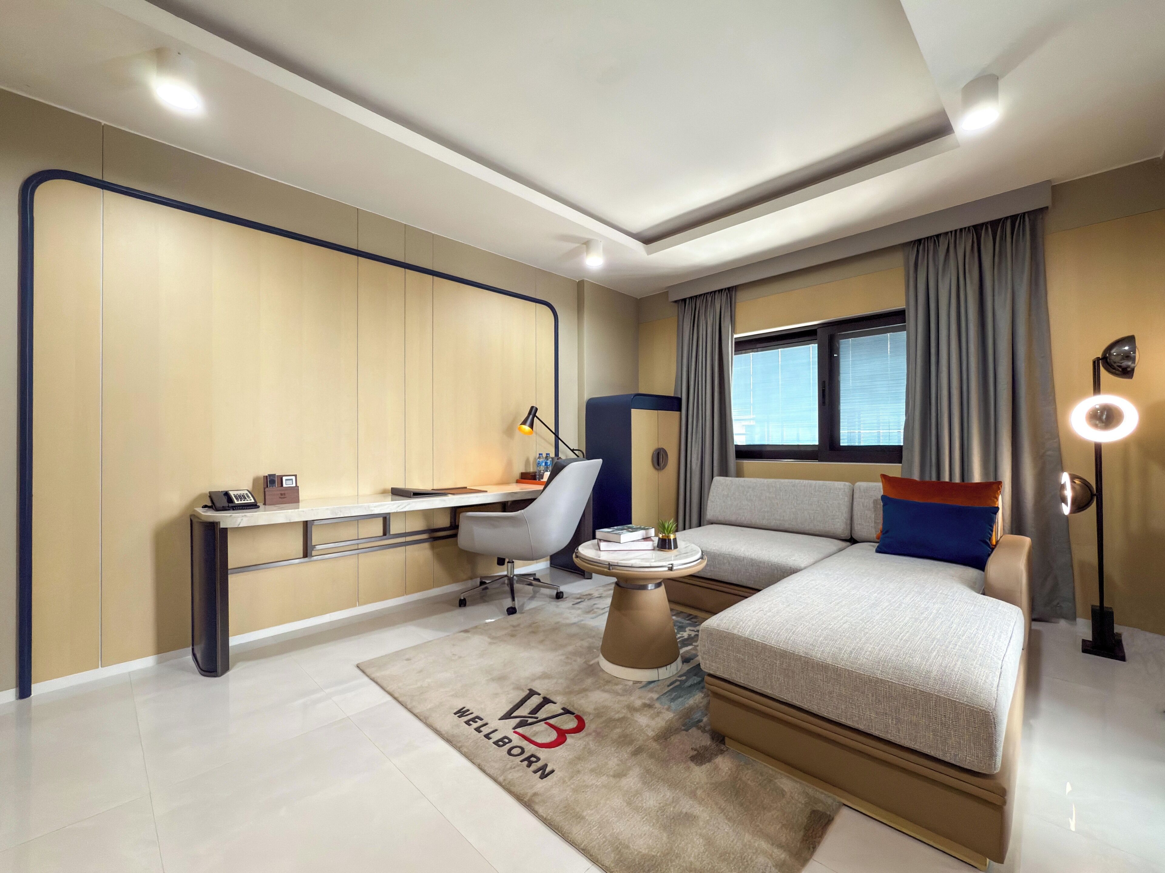 A modern hotel room with a desk, chair, sofa, and a bed.