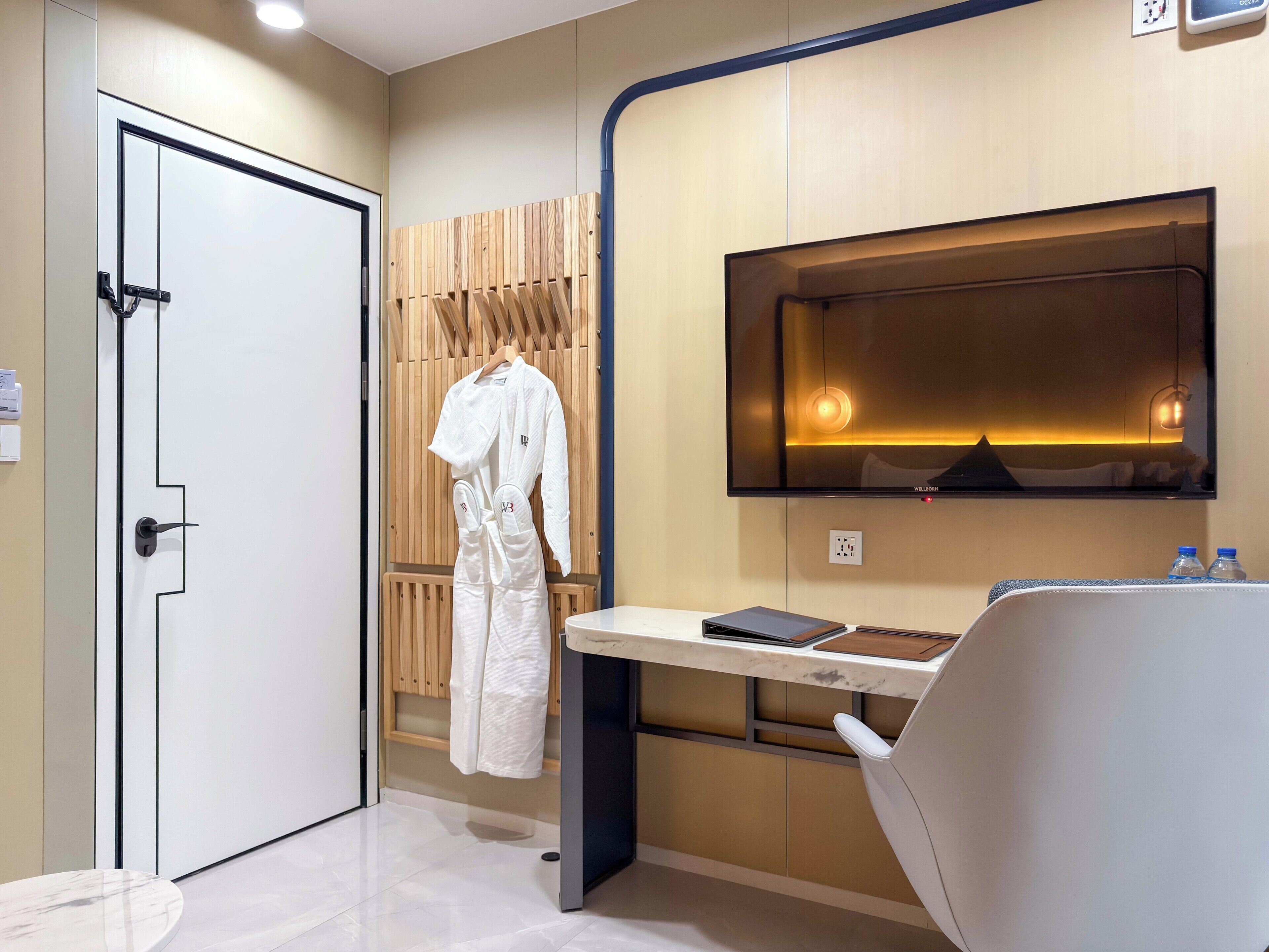 A modern bathroom with a white bathtub, a vanity with a mirror, and a robe hanging on a wooden rack.