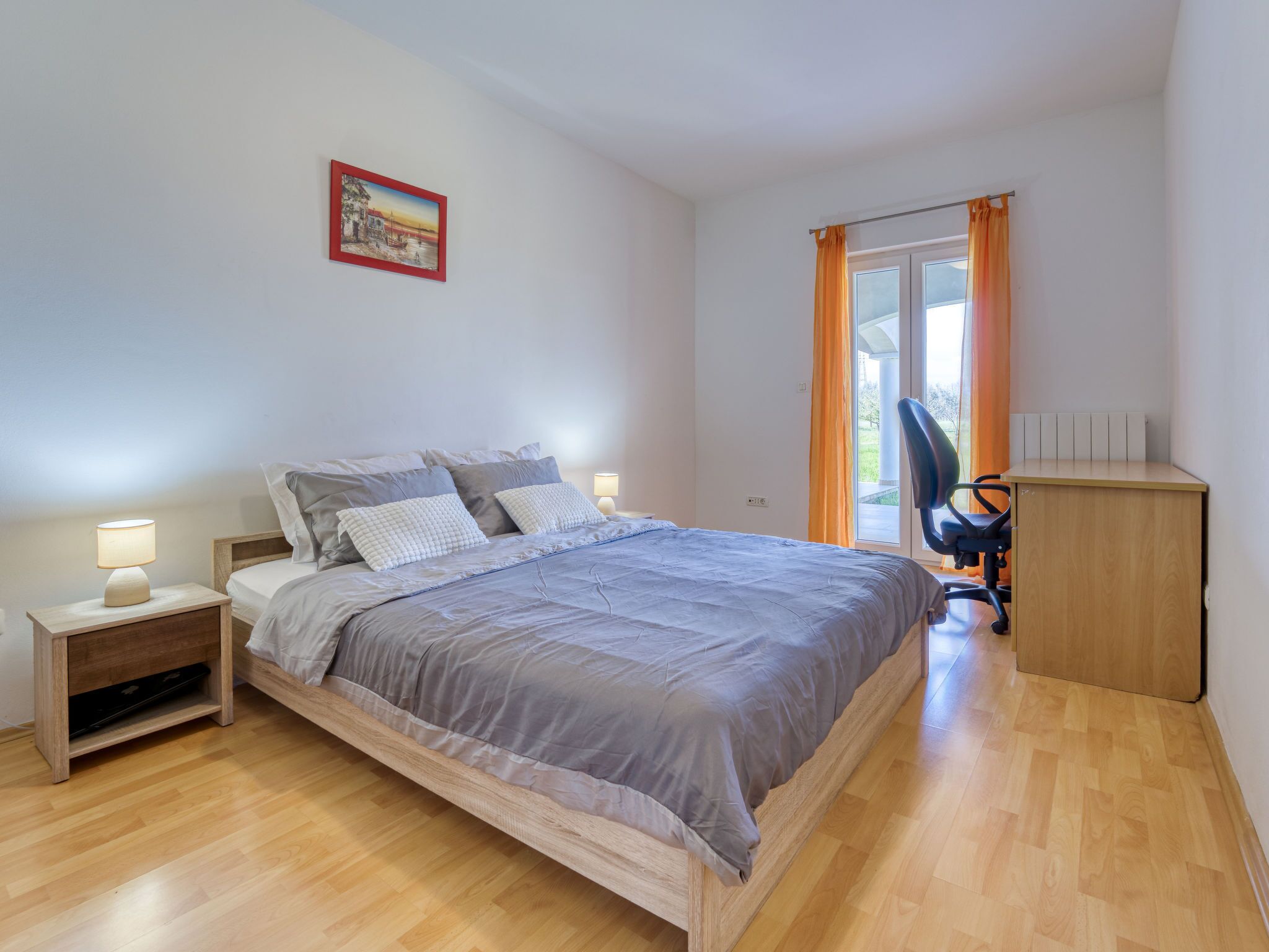 A bedroom with a bed, nightstands, a desk, and a chair.