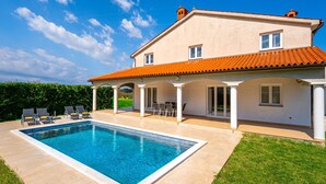 Une maison à deux étages avec une piscine, un patio couvert et un jardin.