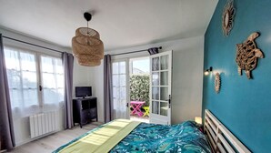 A bedroom with a bed, a TV, a desk, and a balcony with a table and chairs. - Proche Océan, forêt et commerces by Interhome (Fromentine)