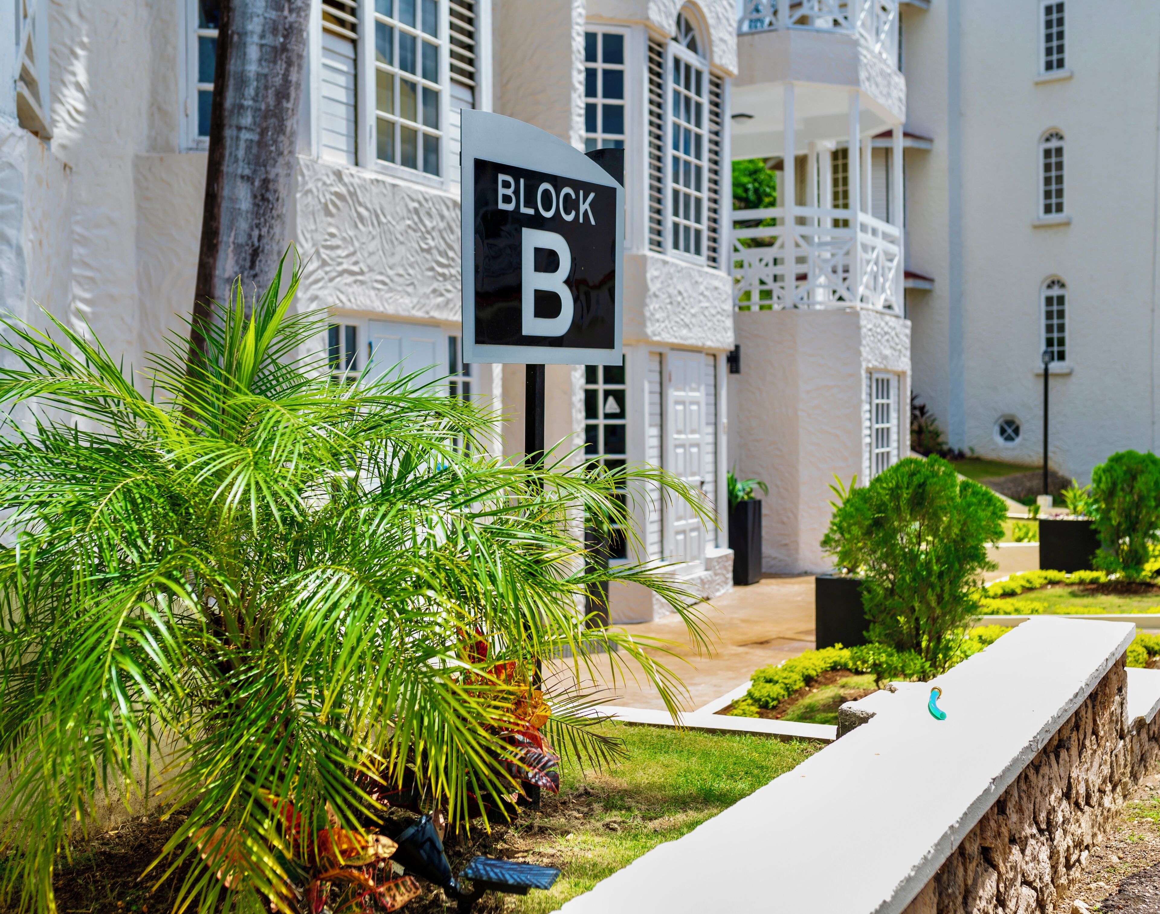 A sign indicating 'BLOCK B' in front of a building with a white exterior and multiple windows.