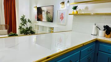 A modern kitchen with white marble countertops, blue cabinets, and a white tiled backsplash.