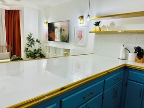A modern kitchen with white marble countertops, blue cabinets, and a white tiled backsplash.