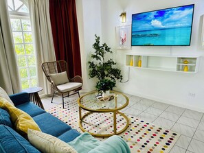 A living room with a sofa, a chair, a TV, a plant, and a round coffee table.