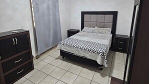 A bedroom with a bed, a nightstand, a wardrobe, and an air conditioning unit. - Full house in subdivision (Juárez)