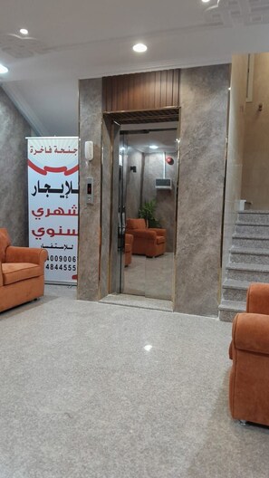 Un hall d’entrée avec un comptoir de réception, un téléphone, une horloge numérique et un escalier.
