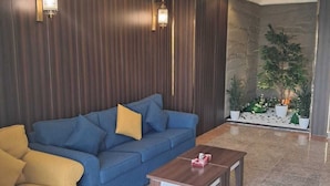 Un salon moderne avec un canapé bleu, un fauteuil jaune et une table basse en bois.