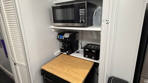 Eine kleine Küche mit Mikrowelle, Kaffeemaschine, Toaster und Geschirrspüler.