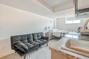 Cozy retreat with a single bed, sofa, and kitchenette.