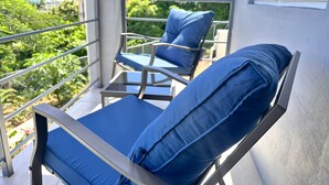 En balkon med to liggestole og et bord, der giver udsigt over et frodigt, grønt landskab.