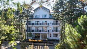A multi-story building with balconies, surrounded by trees.