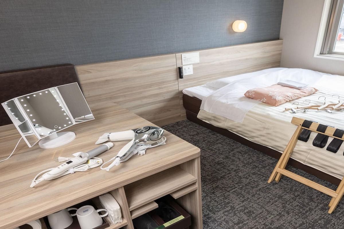 Ein Hotelzimmer mit Bett, Nachttisch, Spiegel und einem kleinen Holzstuhl.