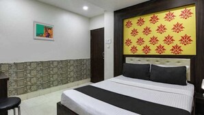 Une chambre d’hôtel avec un grand lit, une tête de lit ornée d’un motif floral, un petit tableau accroché au mur et un décor mural à motifs.