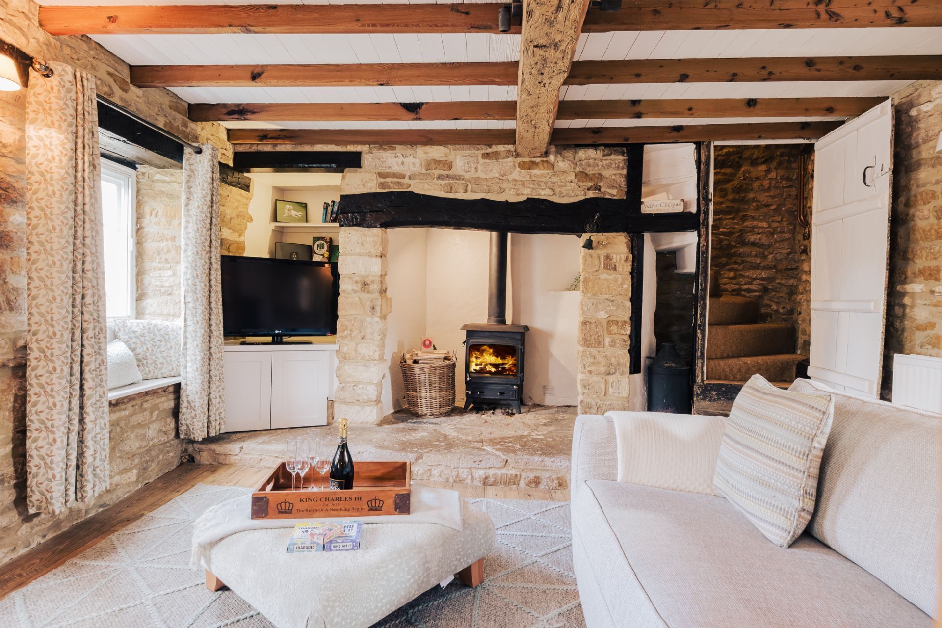 A cozy living room with a stone fireplace, a white sofa, and a wooden ceiling.