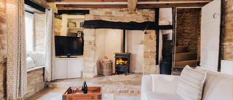A cozy living room with a stone fireplace, a white sofa, and a wooden ceiling.