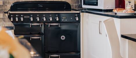 Een keuken met een zwarte RANGERMASTER kookplaat, een witte magnetron en een witte kast.