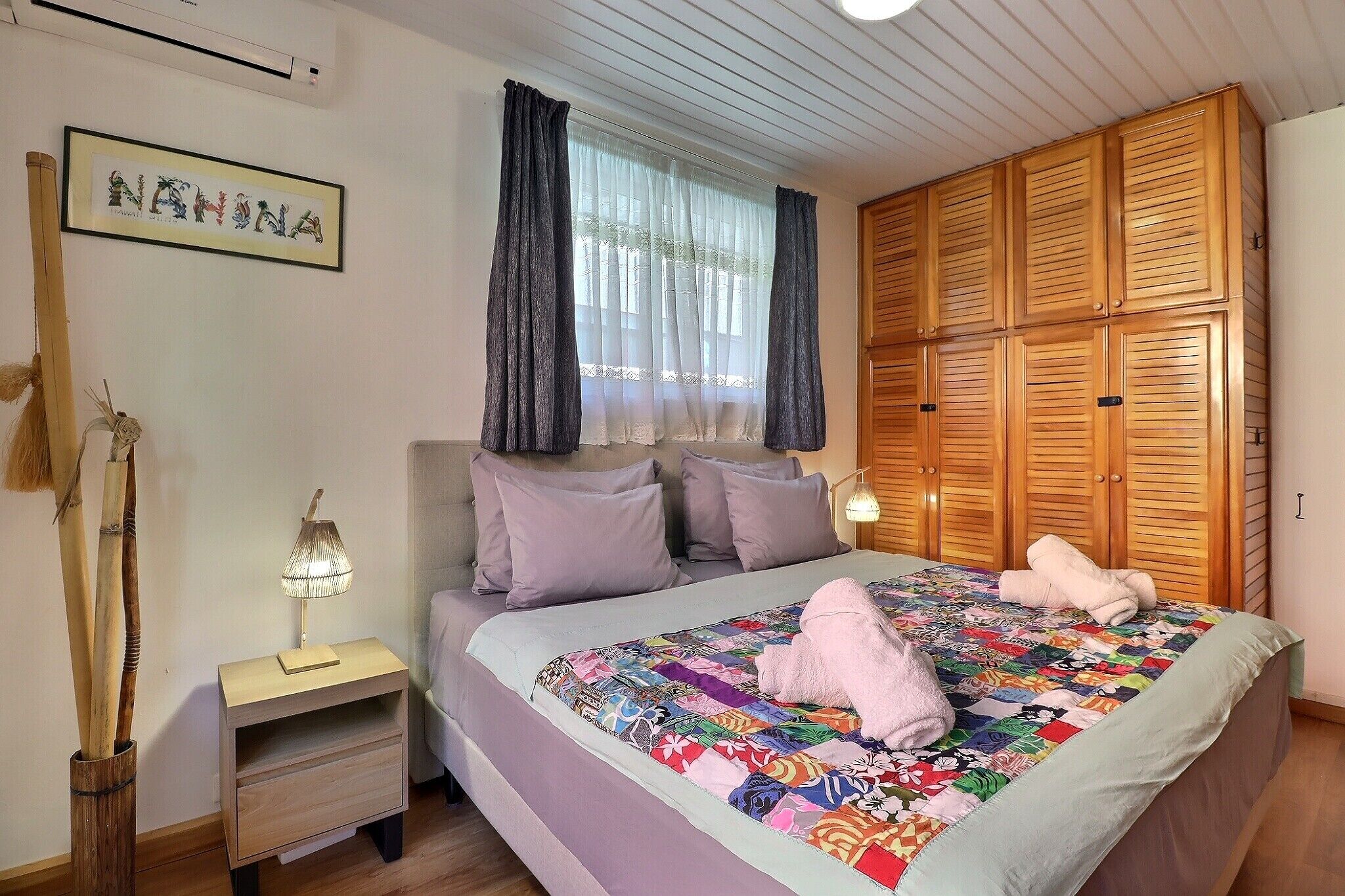Ein Schlafzimmer mit Bett, Nachttisch, Lampe und Kleiderschrank.