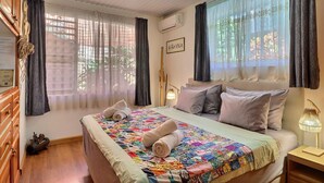 Une chambre d’hôtel avec un lit, une lampe de chevet, une fenêtre avec des rideaux et un climatiseur fixé au mur.