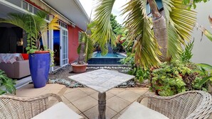 Un espace patio agrémenté d’une table en marbre, de meubles en osier et de différents pots de plantes.