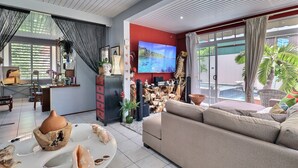 Un salon moderne comprenant un canapé, un téléviseur et un coin repas avec une table et des objets décoratifs.